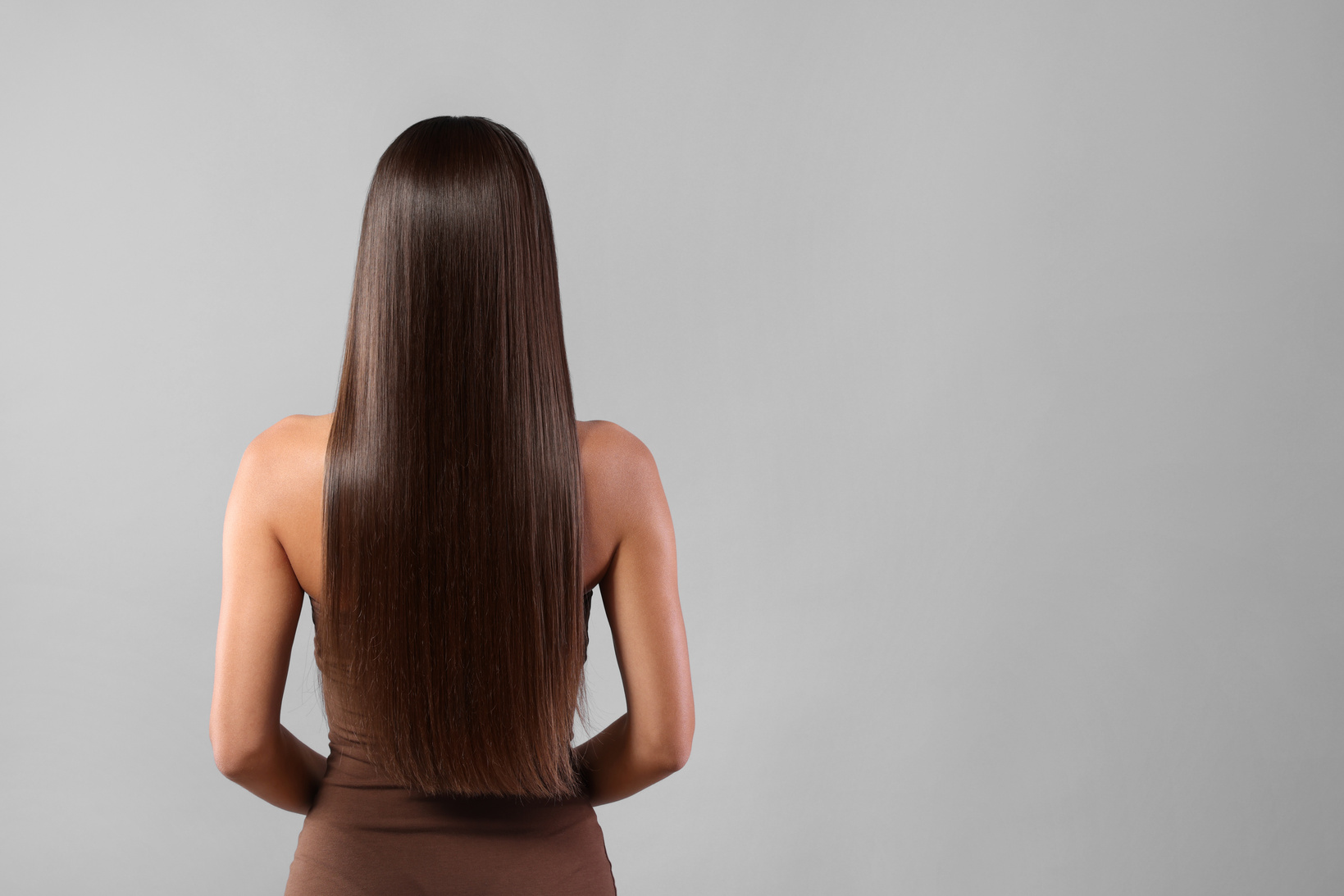 Hair Styling. Woman with Straight Long Hair on Grey Background,