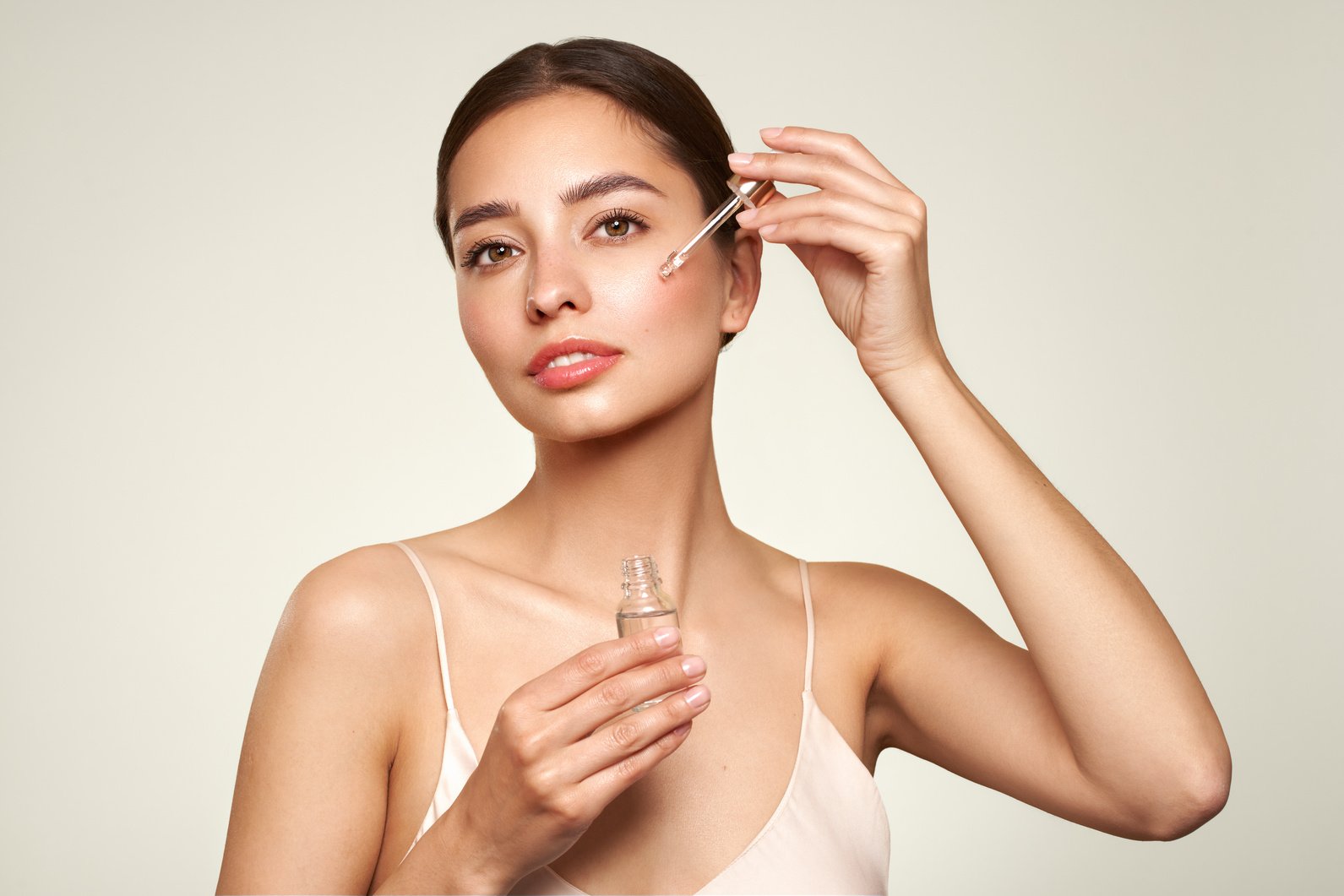 Young beautiful woman applying face serum