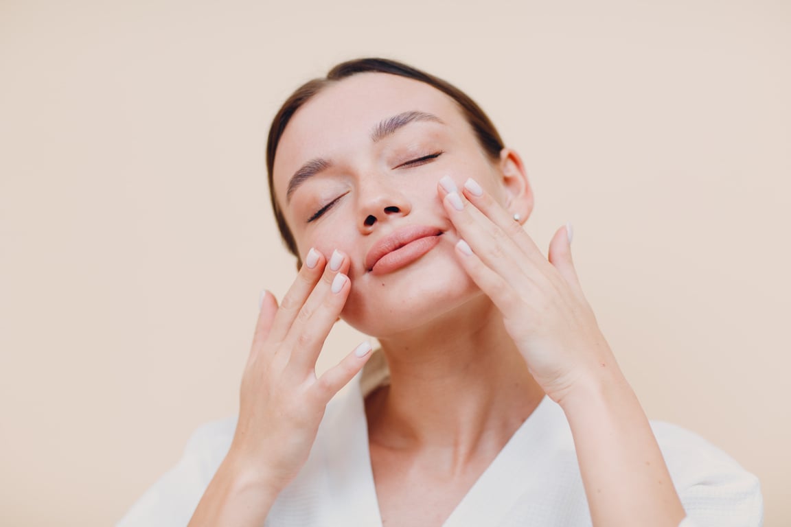 Young Woman Applying Cosmetic Cream on Her Face