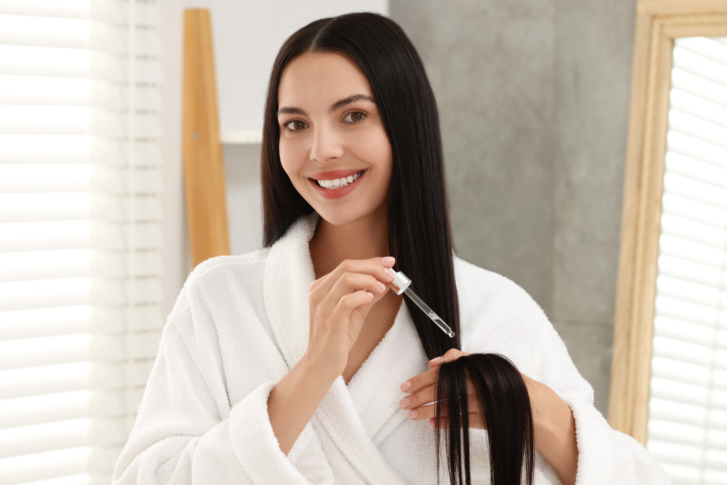 Beautiful Woman Applying Hair Serum Indoors. Cosmetic Product